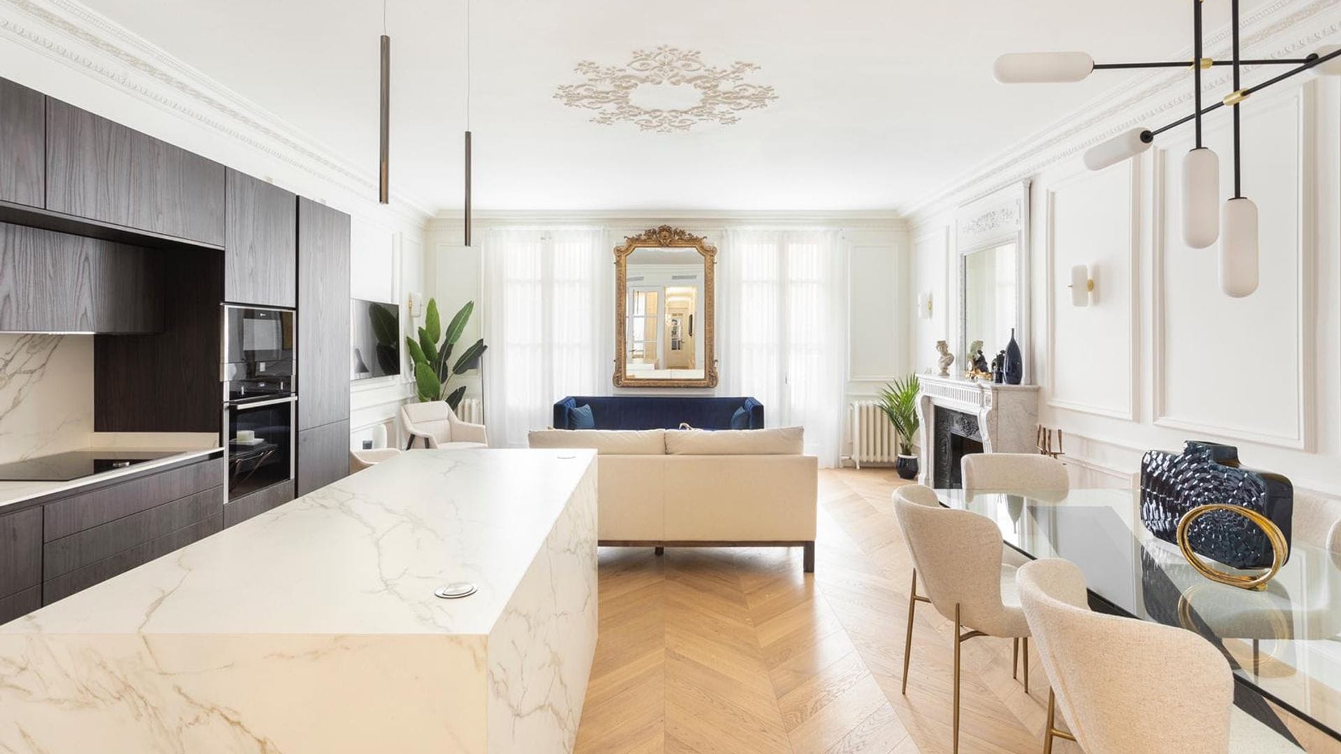 Salón comedor y cocina con suelo de madera, molduras y espejo dorado