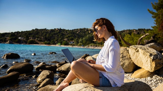 Una mujer en la playa con un portátil