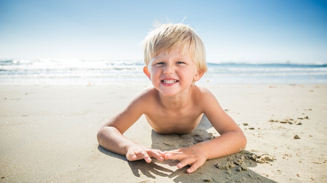 Niño tumbado en la arena de la playa