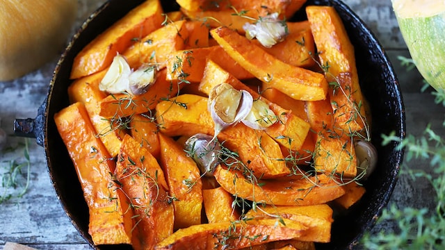 baked pumpkin slices in a pan with herbs and garlic