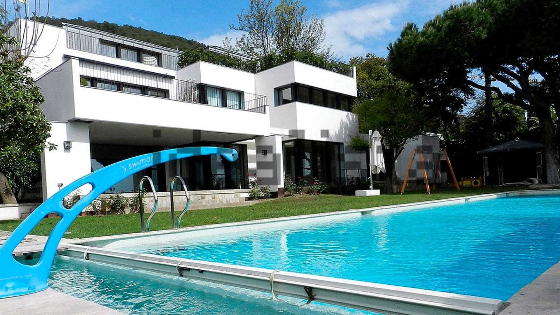 Jardín con piscina rectangular y pieza metálica azul 