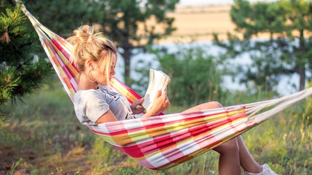mujer leyendo relajada en una hamaca en el campo