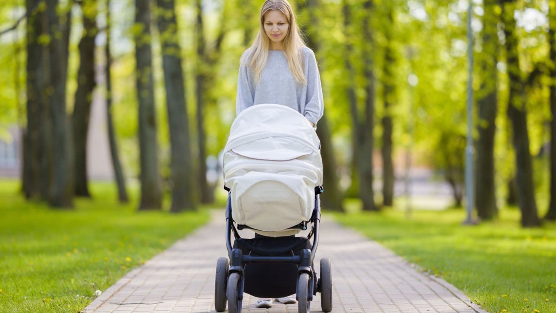 madre paseando a su beb por el parque en cochecito en verano 