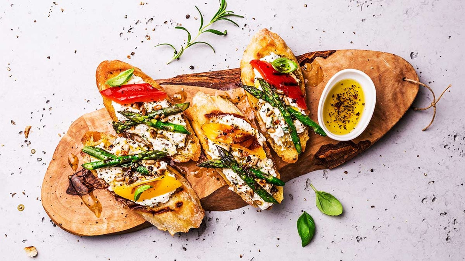 Tostas de queso, espárragos y pimientos con piñones