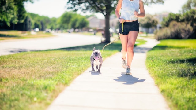 Una chica corriendo por la calle con su perro