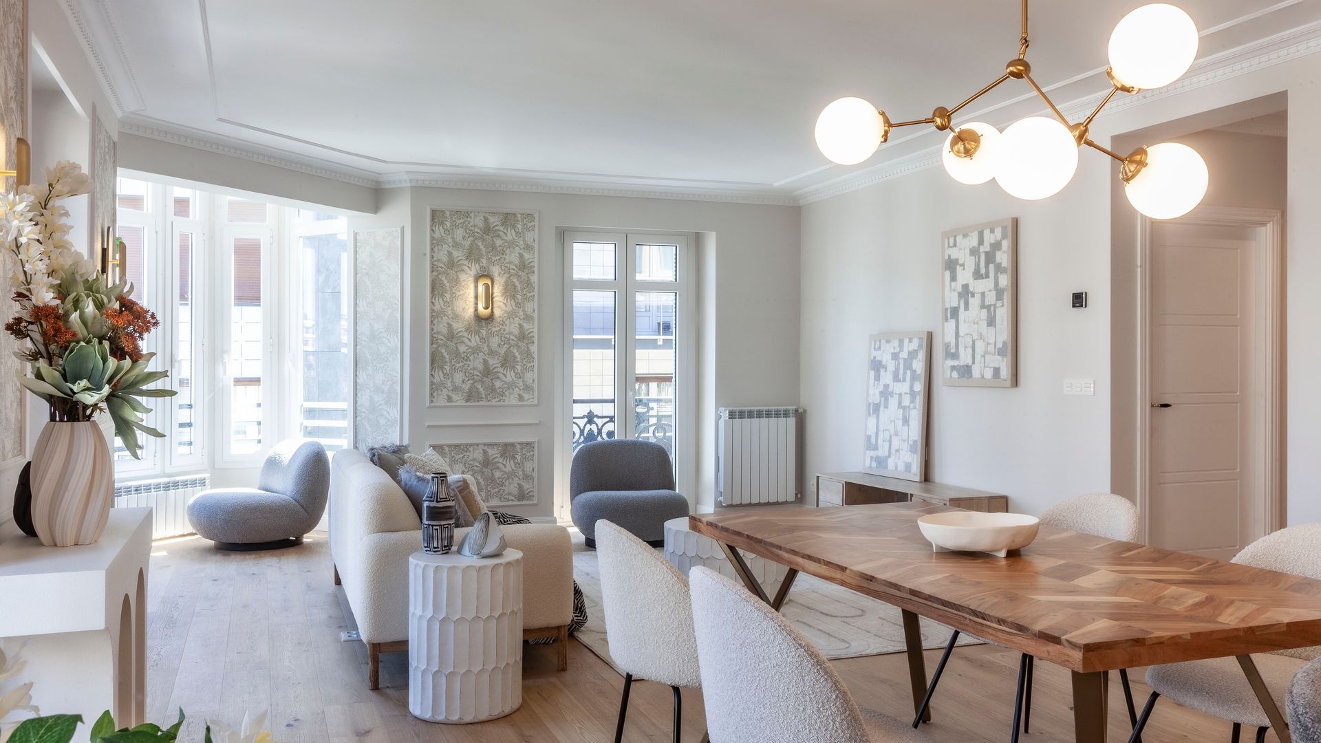 Salón comedor con mesa de madera, sillas blancas y lámpara de suspensión retro