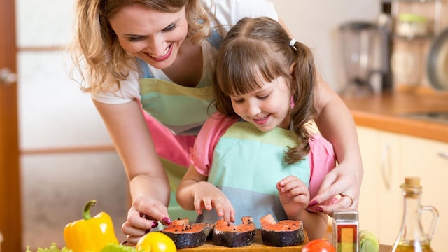 ni a cocinando pescado con su madre