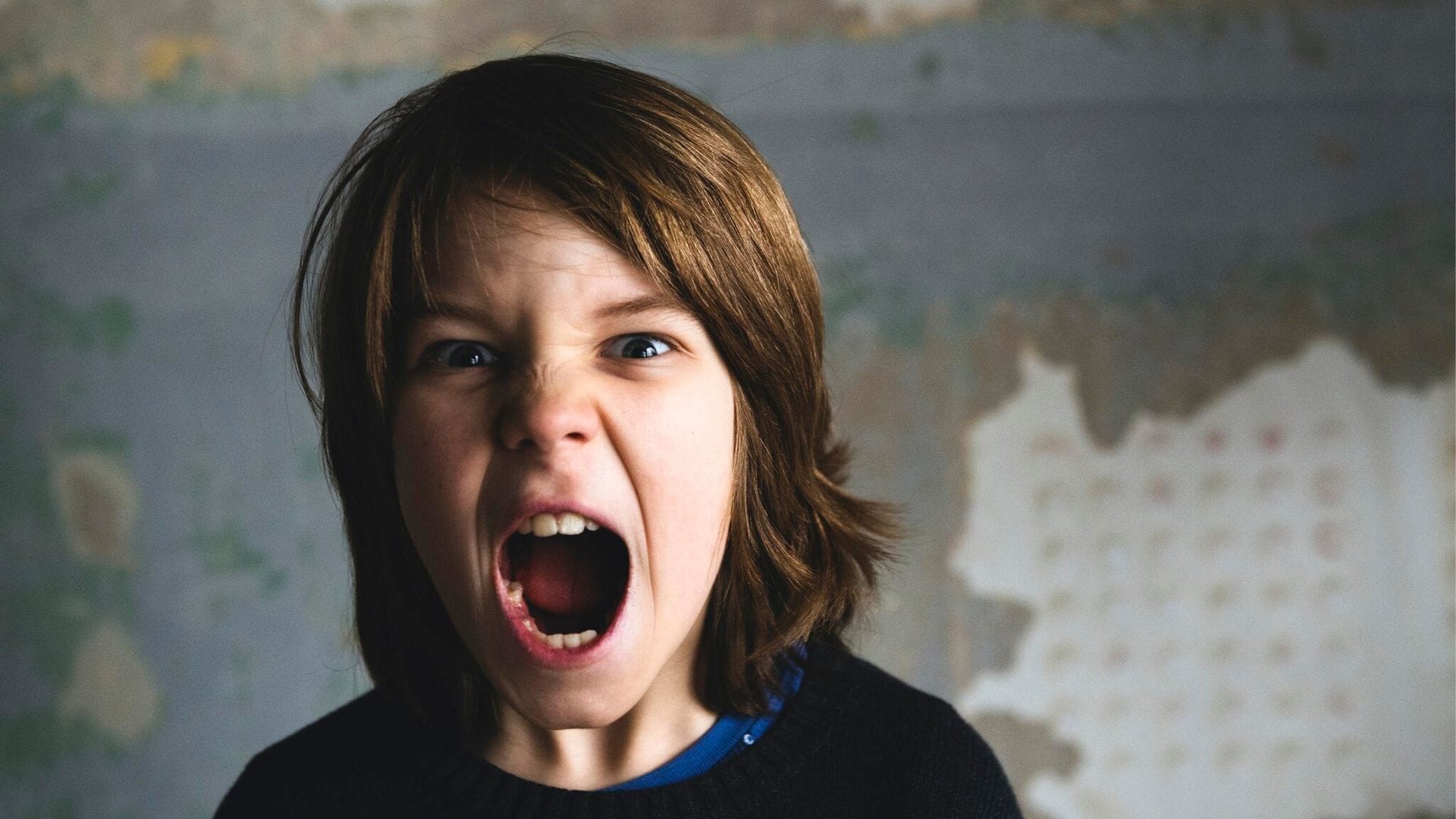 boy screaming against rusty wall