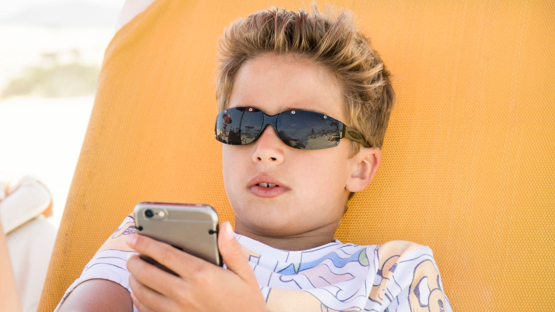 Adolescente con el móvil en la playa