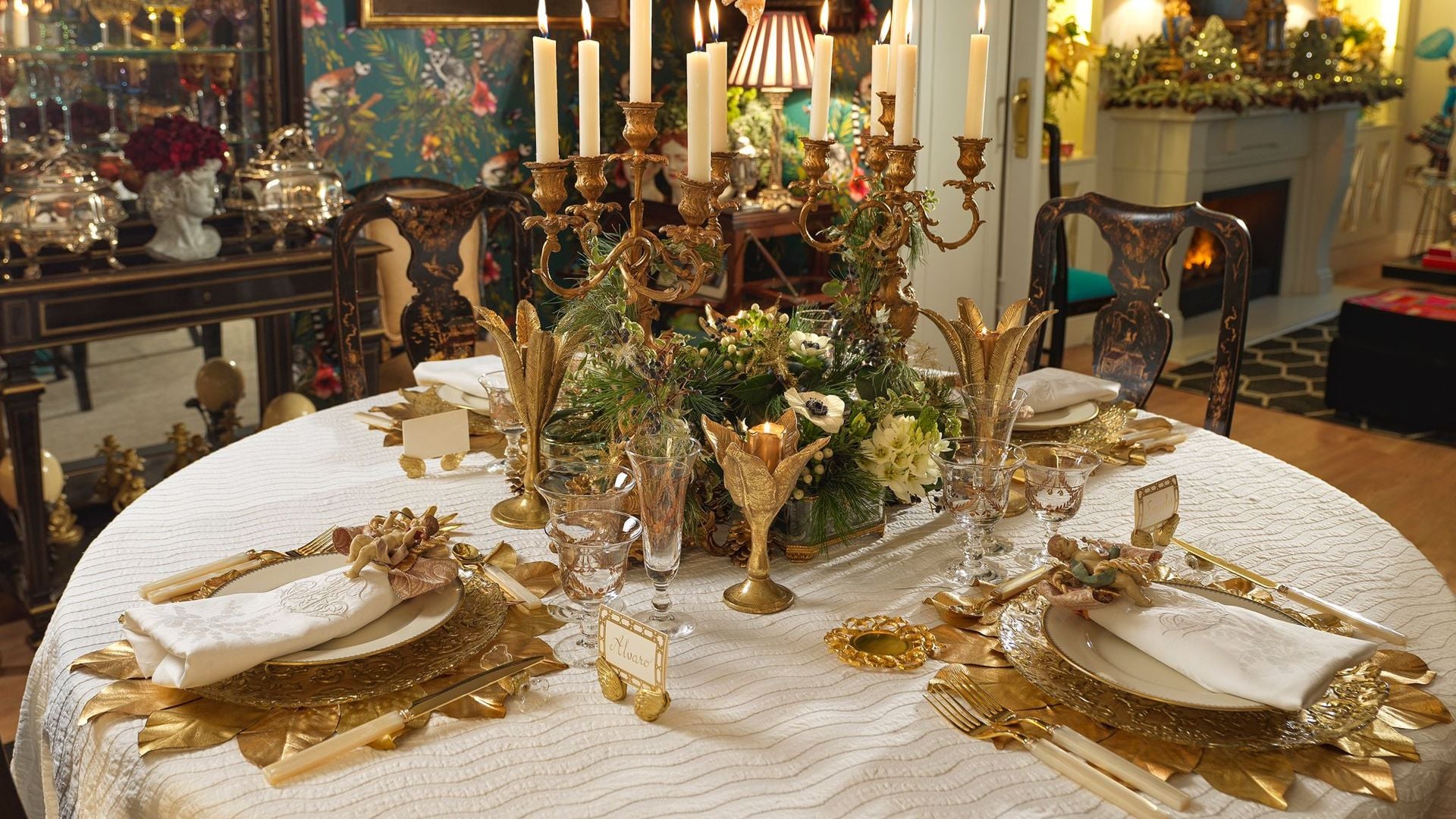 Mesa de Navidad con mantel blanco, cubiertos dorados, candelabros dorados 