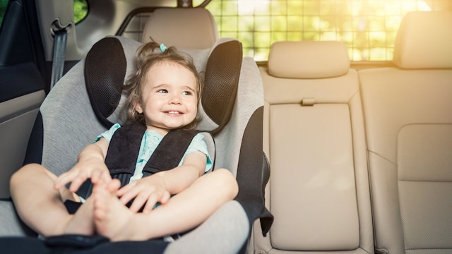 ni a sonriendo en el coche sentada en una silla adaptada 