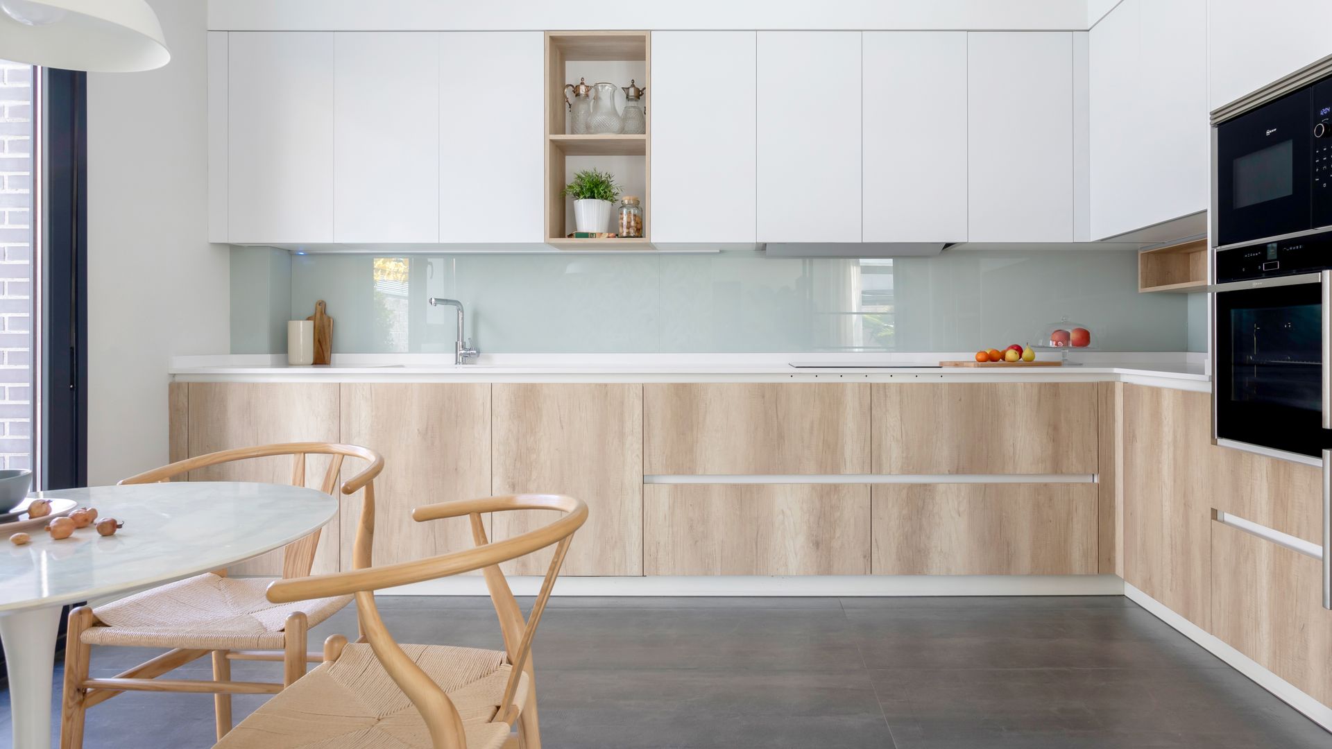 Cocina con muebles de madera y blancos, office, suelo gris y antepecho de cristal traslúcido