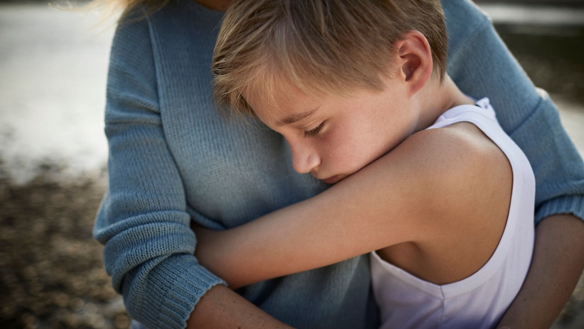 Niño muy triste abrazado a su madre