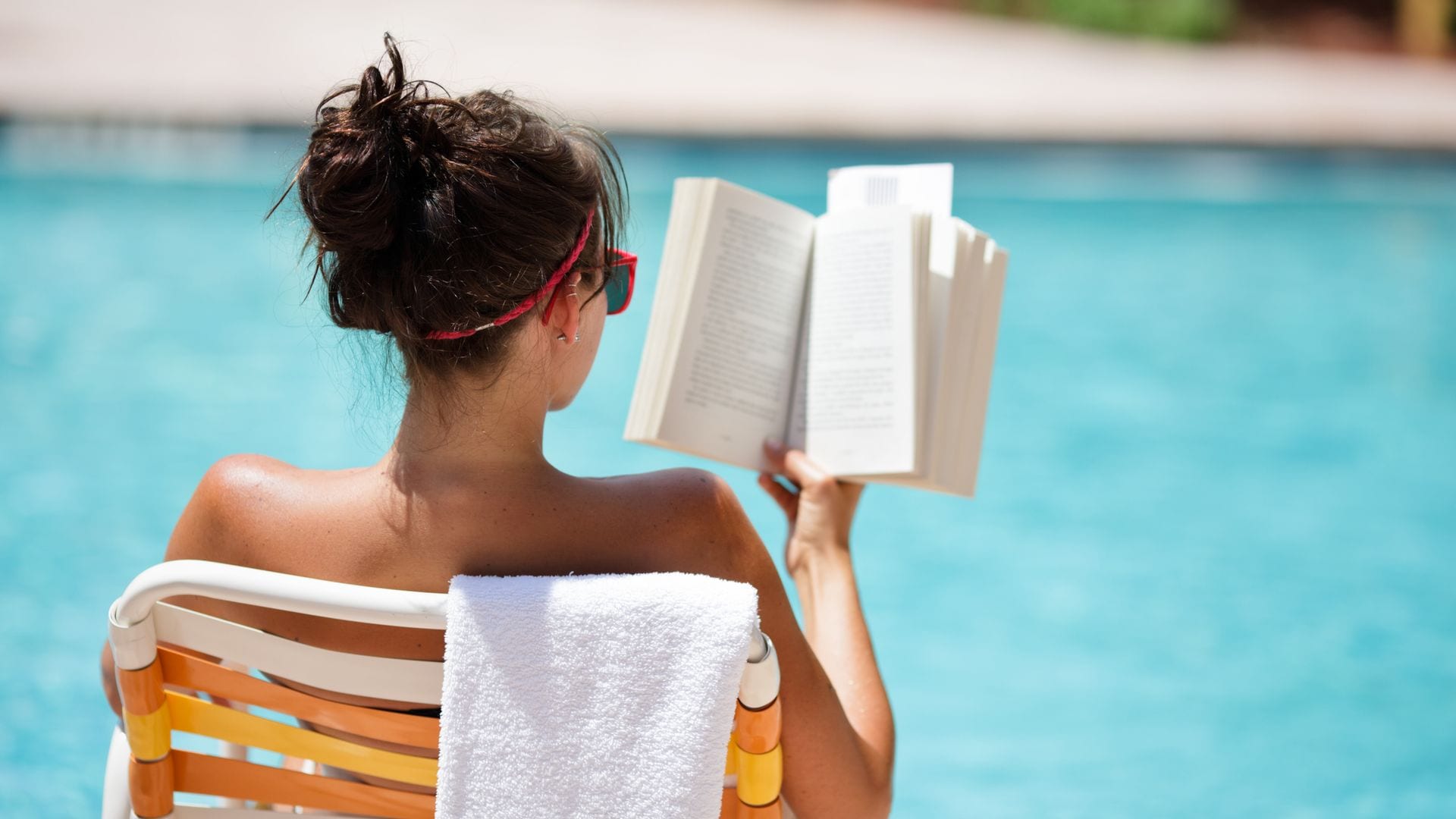 Mujer leyendo un libro en la piscina