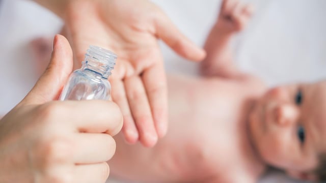 mano con bote de aceite preparada para dar masaje a un beb 