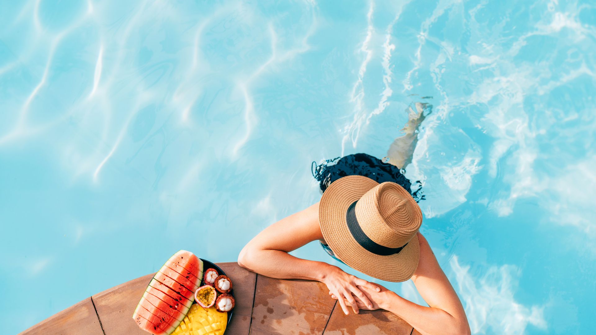 Mujer en la piscina tomando frutas tropicales 