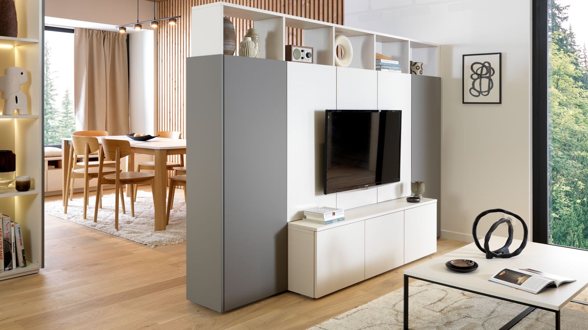 Mueble blanco y gris que alberga televisión y actúa como separador con la cocina 