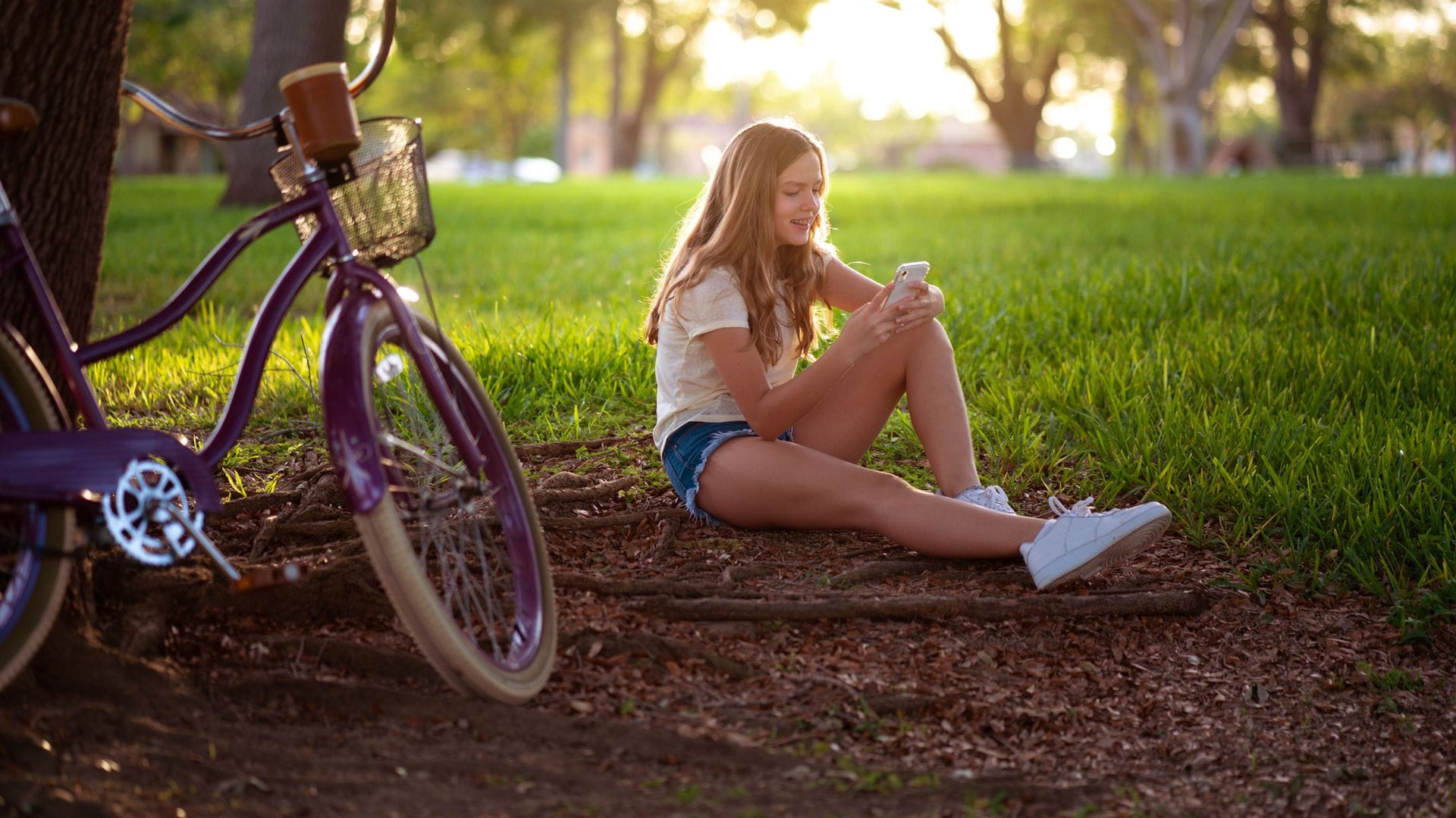 Adolescente con el móvil en un parque