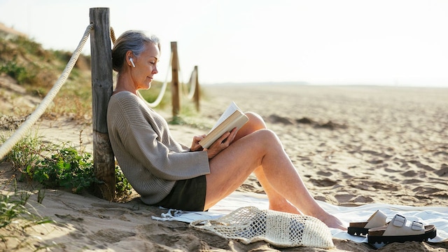 mujer madura lee playa