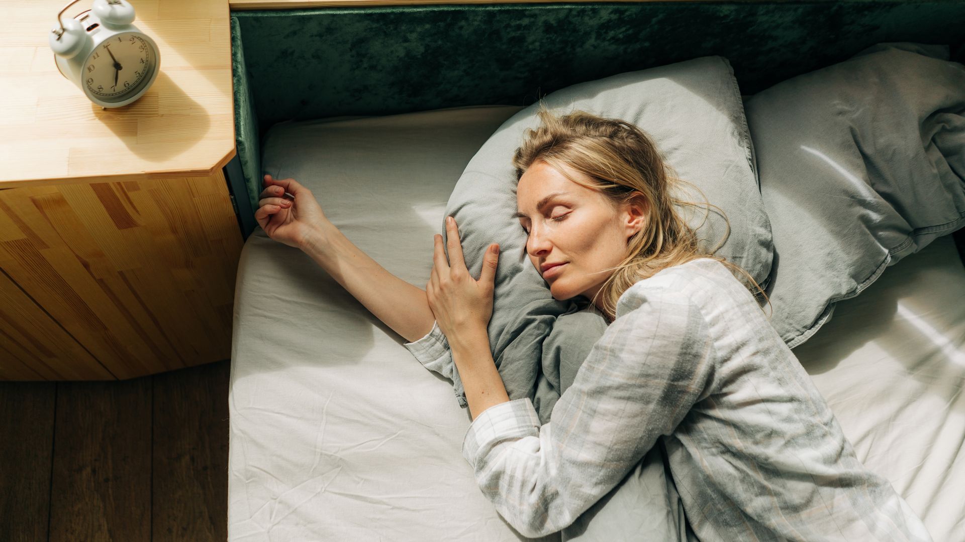 mujer en la cama durmiendo, con el despertador en la mesilla