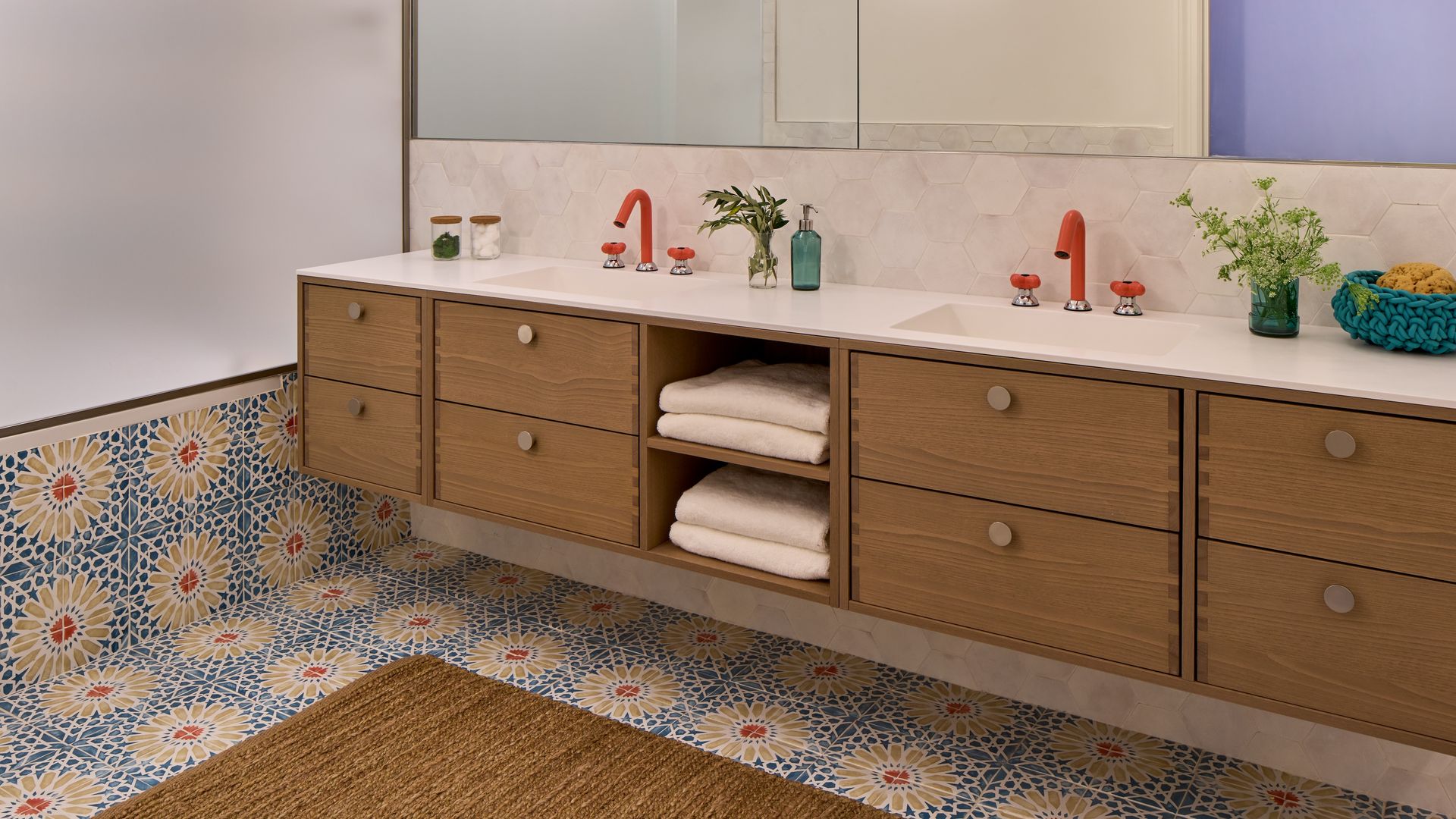 Baño con lavamanos doble, bañera. mueble bajolavabo de madera, grados rojos y suelo y revestimiento de azulejos en azul y rojo