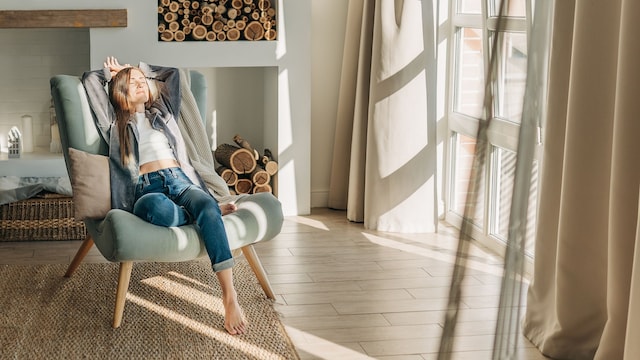 mujer relajada sentada en un sillón junto a la ventana