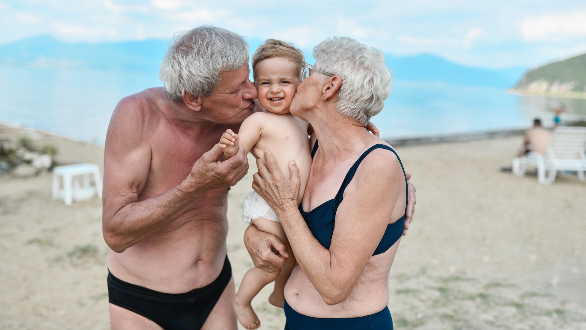 Dos abuelos besan a su nieto en la playa