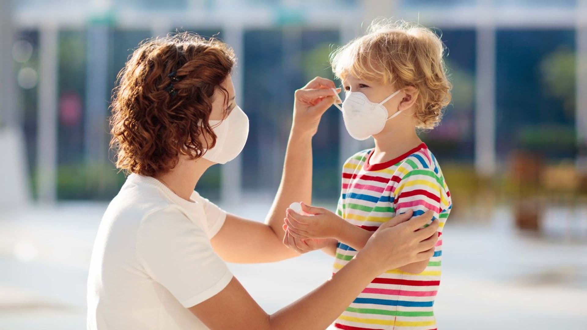 madre poni ndole a su hijo la mascarilla en la calle 