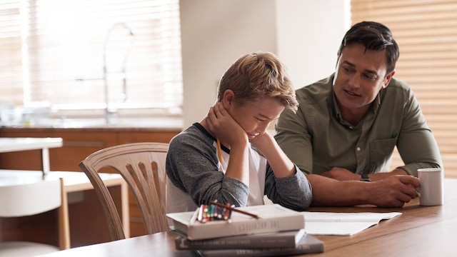 hijo haciendo los deberes con su padre en el escritorio 