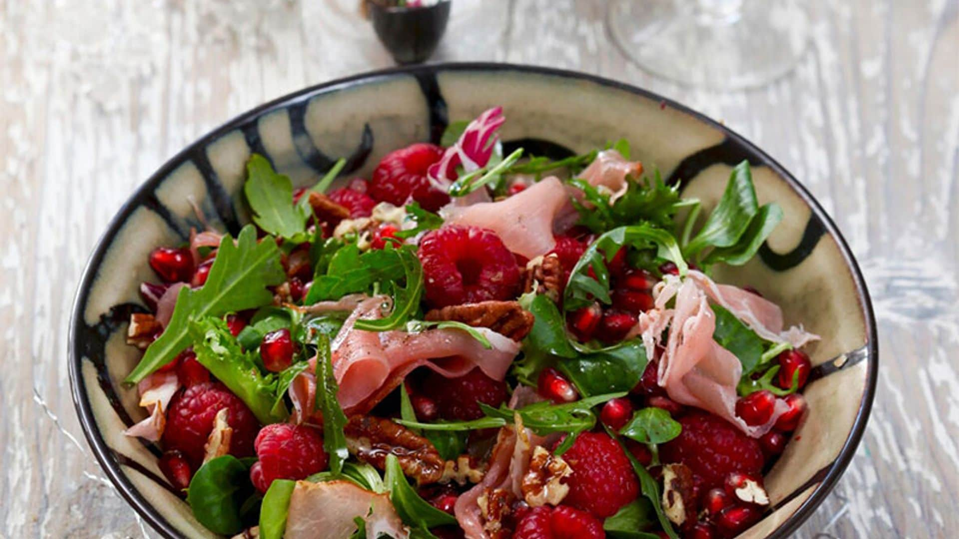 Ensalada de rúcula, frambuesas, granada, nueces pecanas y jamón