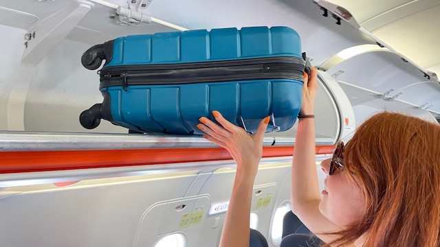Mujer subiendo maleta en el avión
