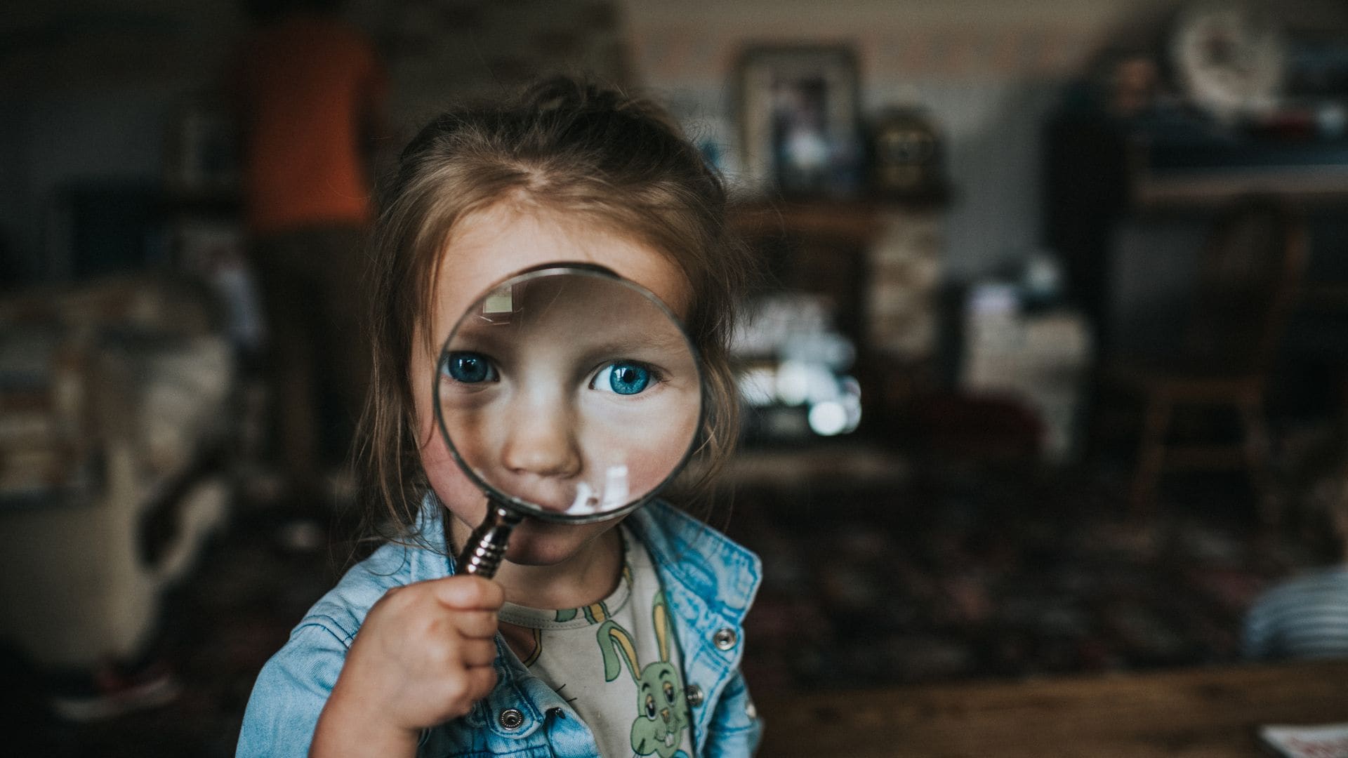 Niña observa a travñes de una lupa