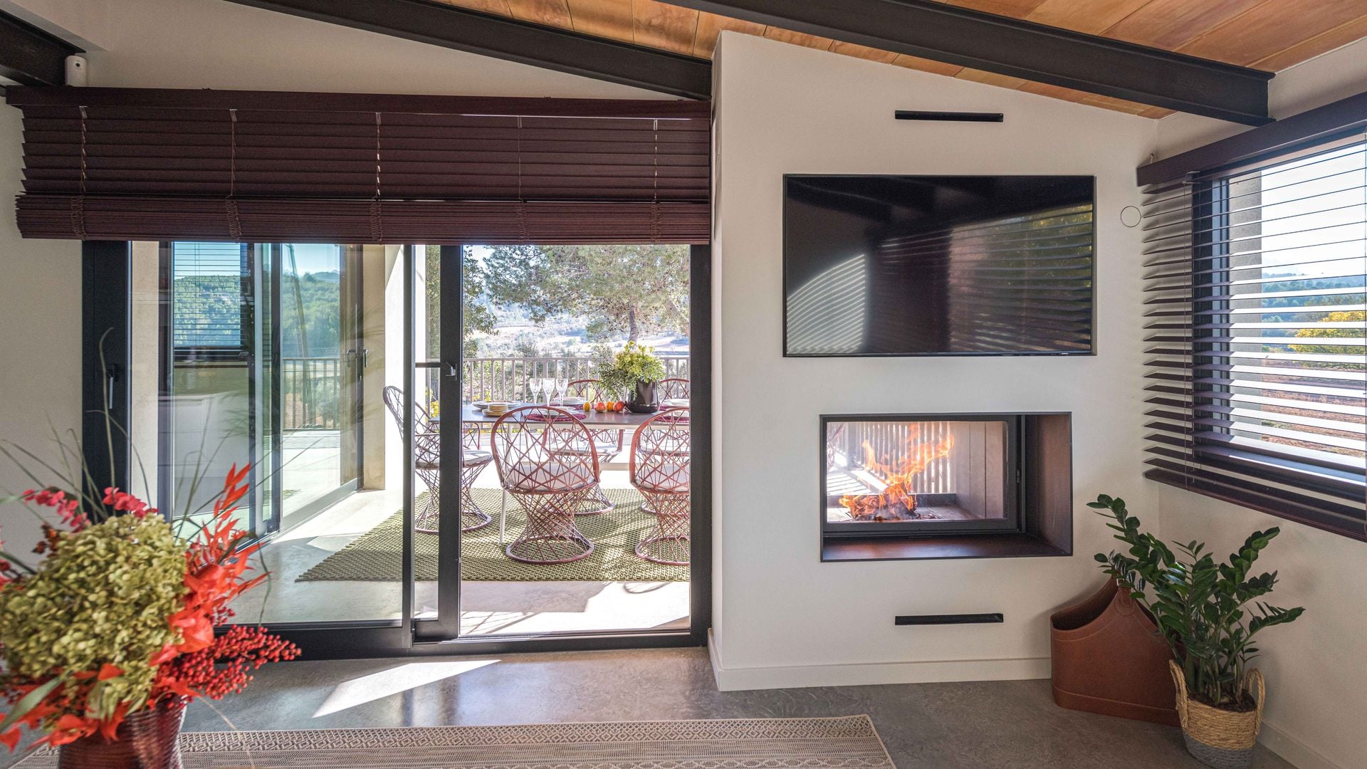 Salón con chimenea vista con salida a la terraza y televisión en la pared