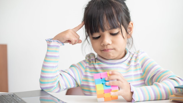 Niña pequeña sosteniendo un cubo de Rubik en sus manos. El cubo de Rubik es un juego que aumenta la inteligencia de los niños.