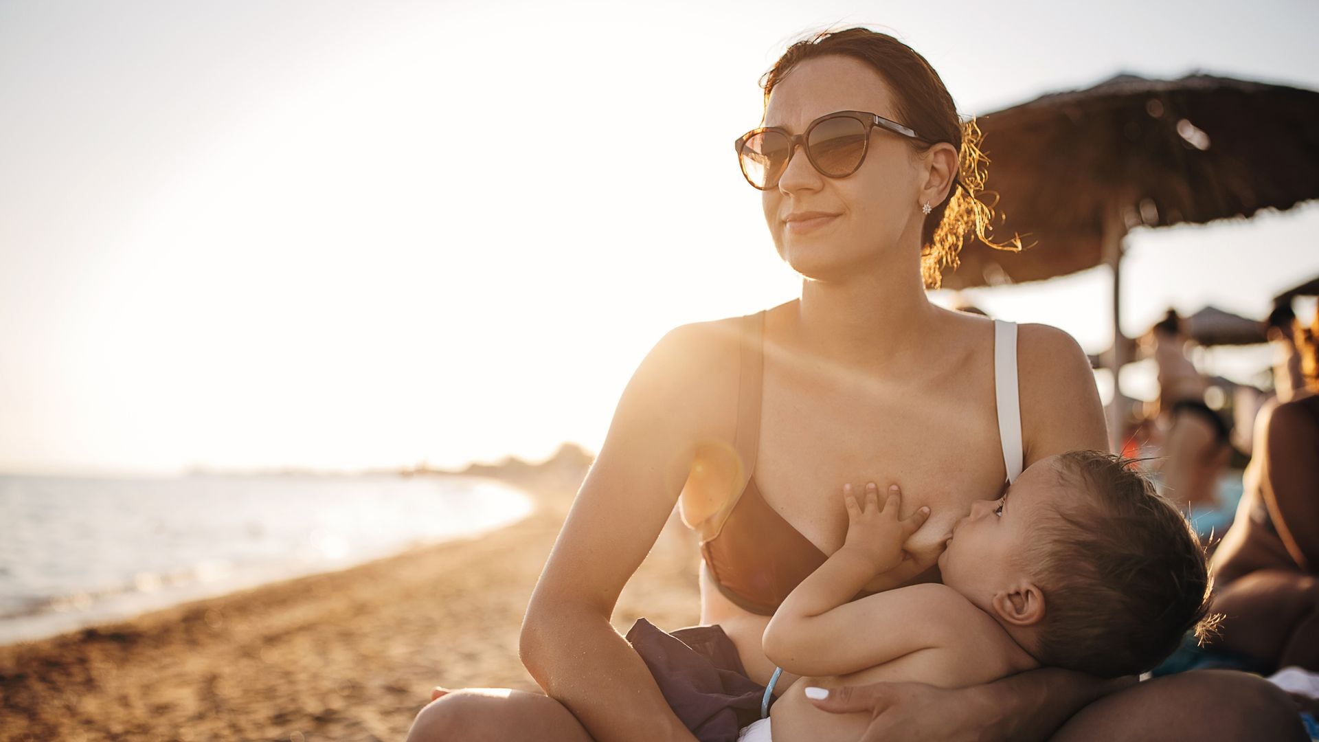 Madre da el pecho a su bebé en la playa