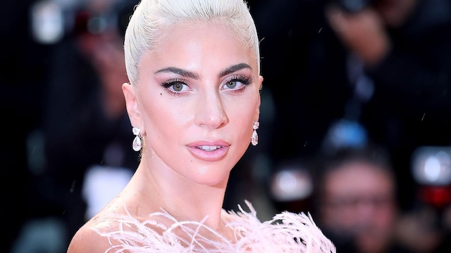 lady gaga con pelo recogido platinado vestida de plumaje