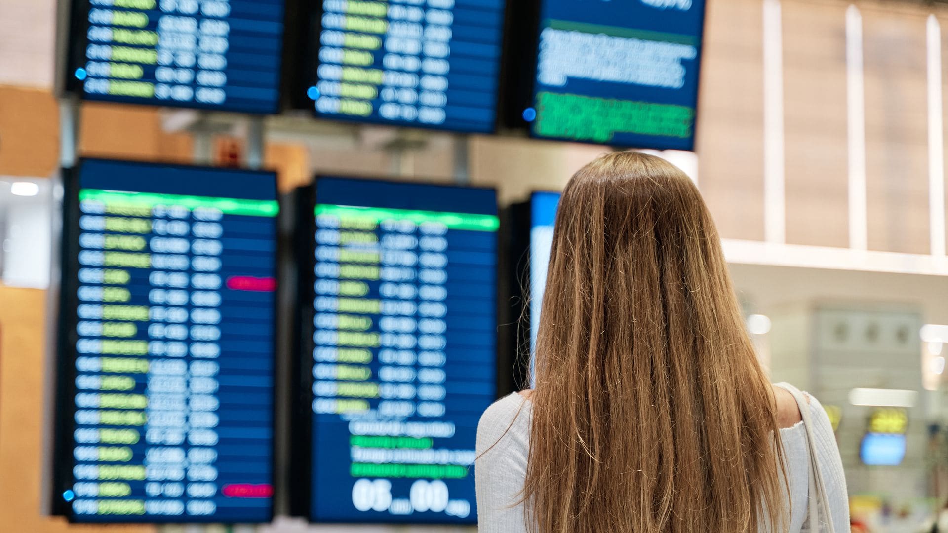 Mujer en el aeropuerto comprobando los paneles de salidas para viajar en avión