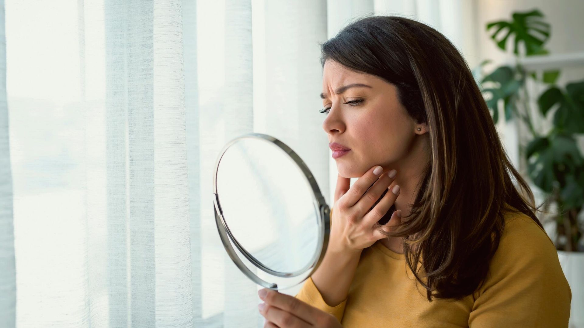 mujer mirandose el rostro en un espejo