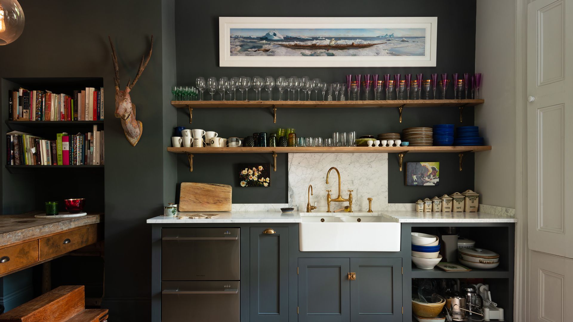 Cocina clásica en color gris, con grifo dorado, fregadero antiguo y baldas con vasos, tazas y accesorios 