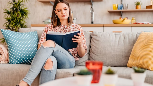 mujer leyendo concentrada un libro en el sofá