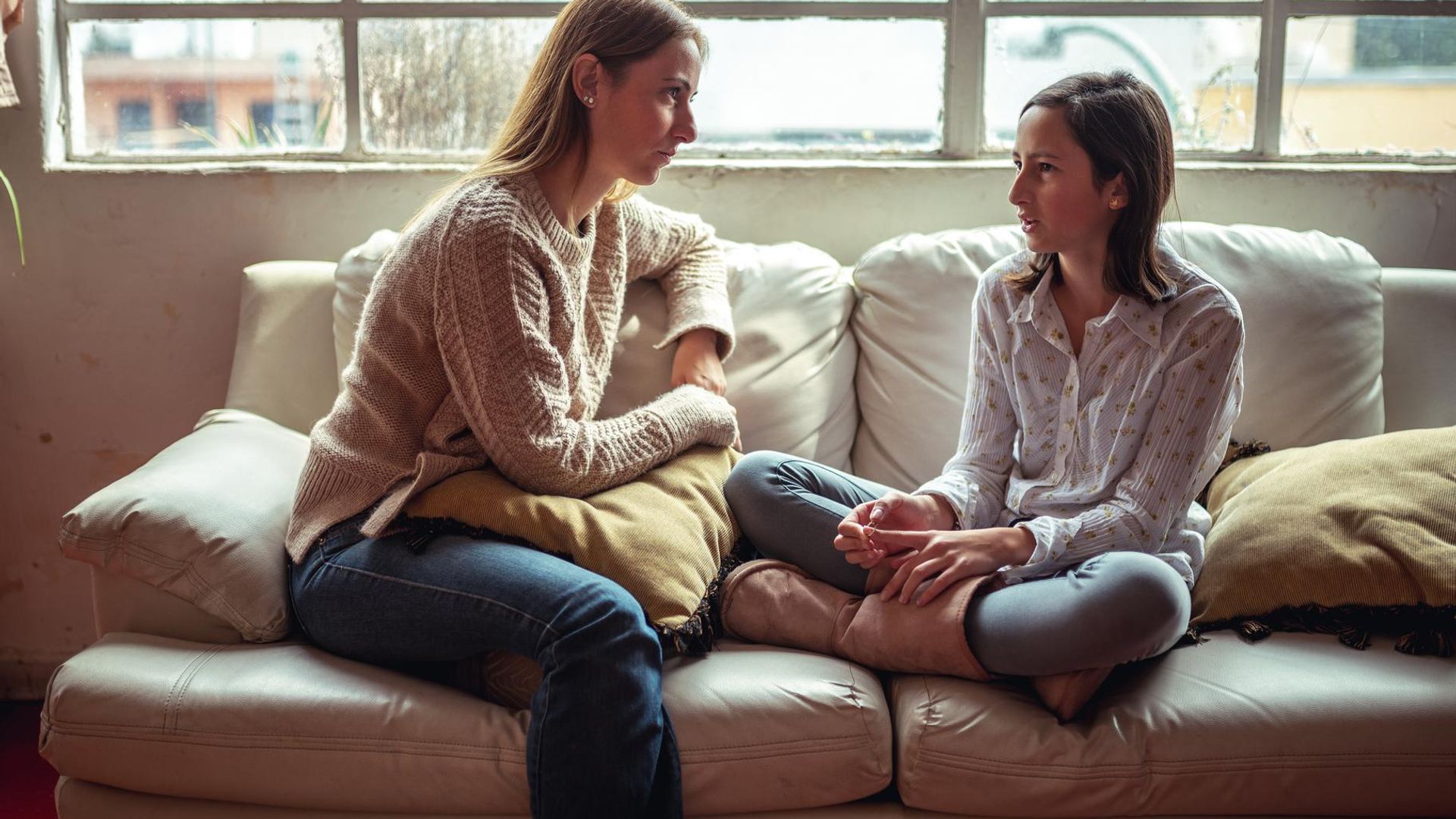 madre e hija hablando en el sof de casa 