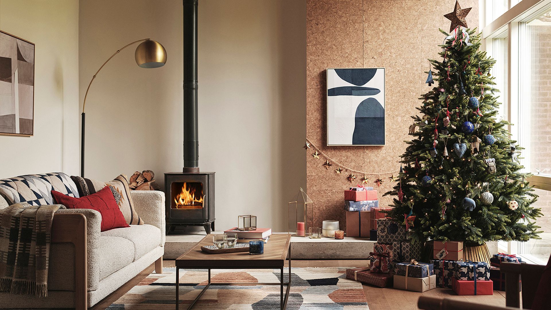 Salón  con chimenea, árbol de Navidad, pared de corcho y lámpara arco dorada