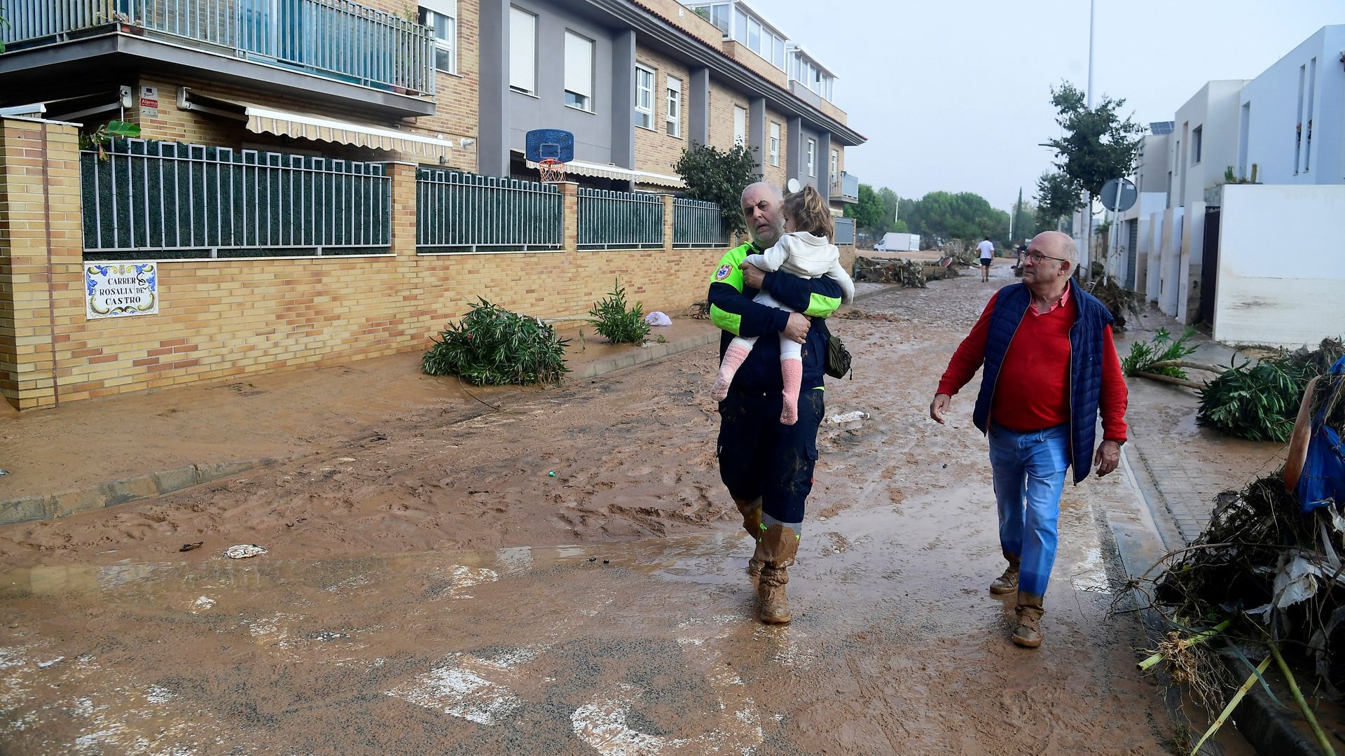 Un agente de protección civil lleva a una niña en brazos por las calles llenas de lodo de Pincaña (Valencia) tras el paso de la DANA