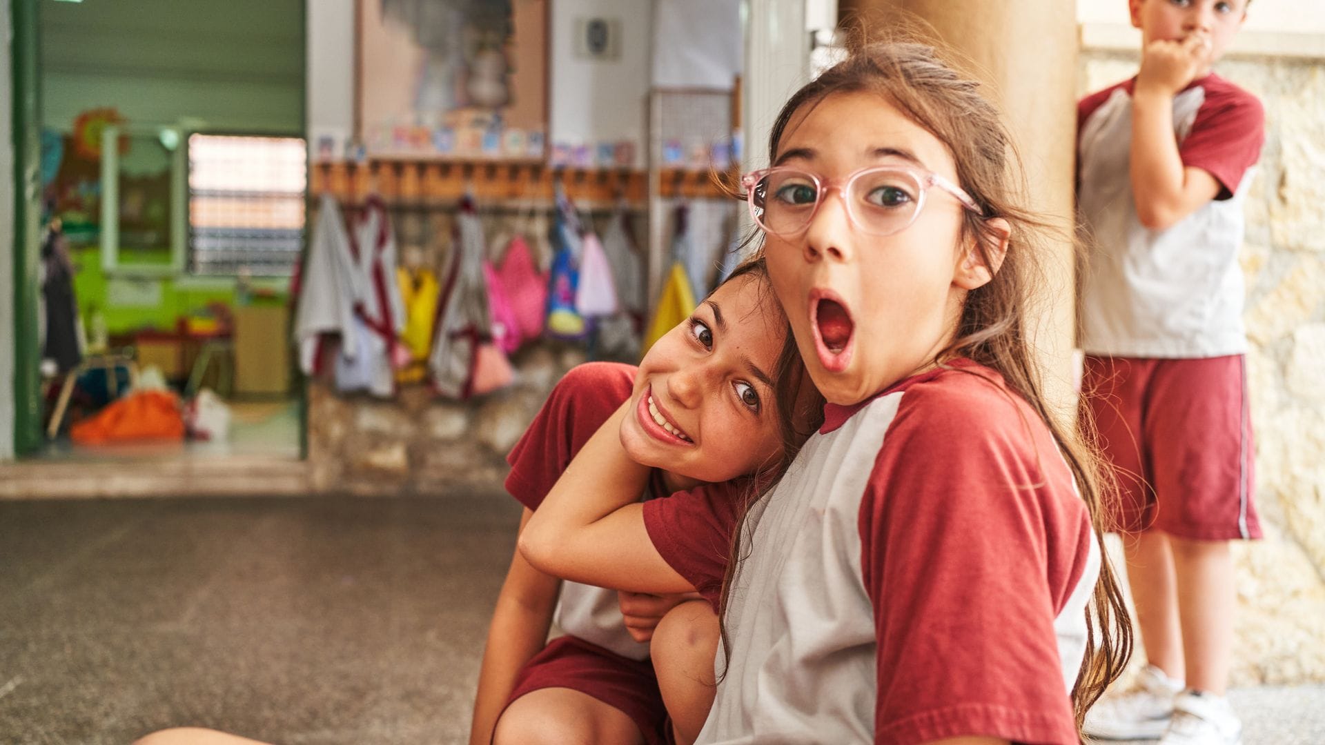 Niña pone cara de asombro mientras abraza a su amiga