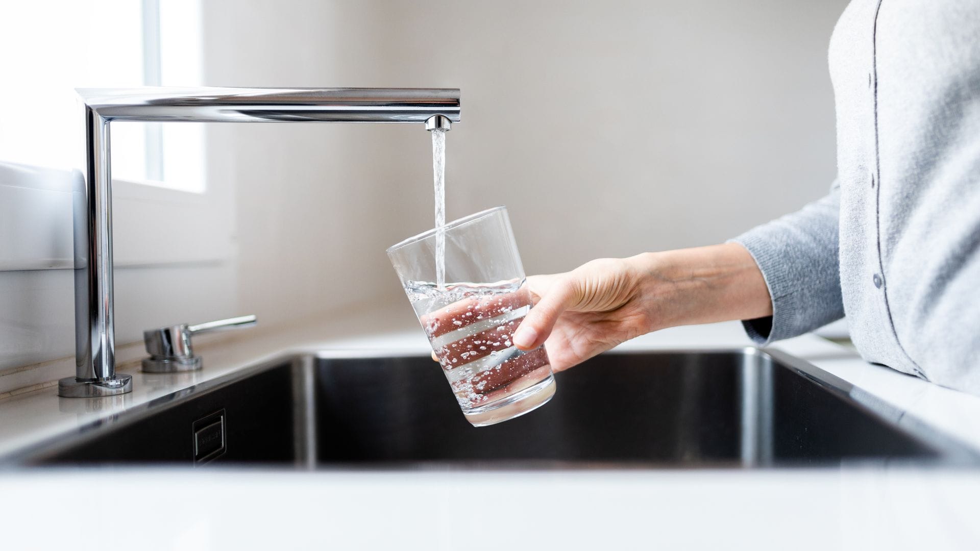 Una mujer llenando un vaso de agua