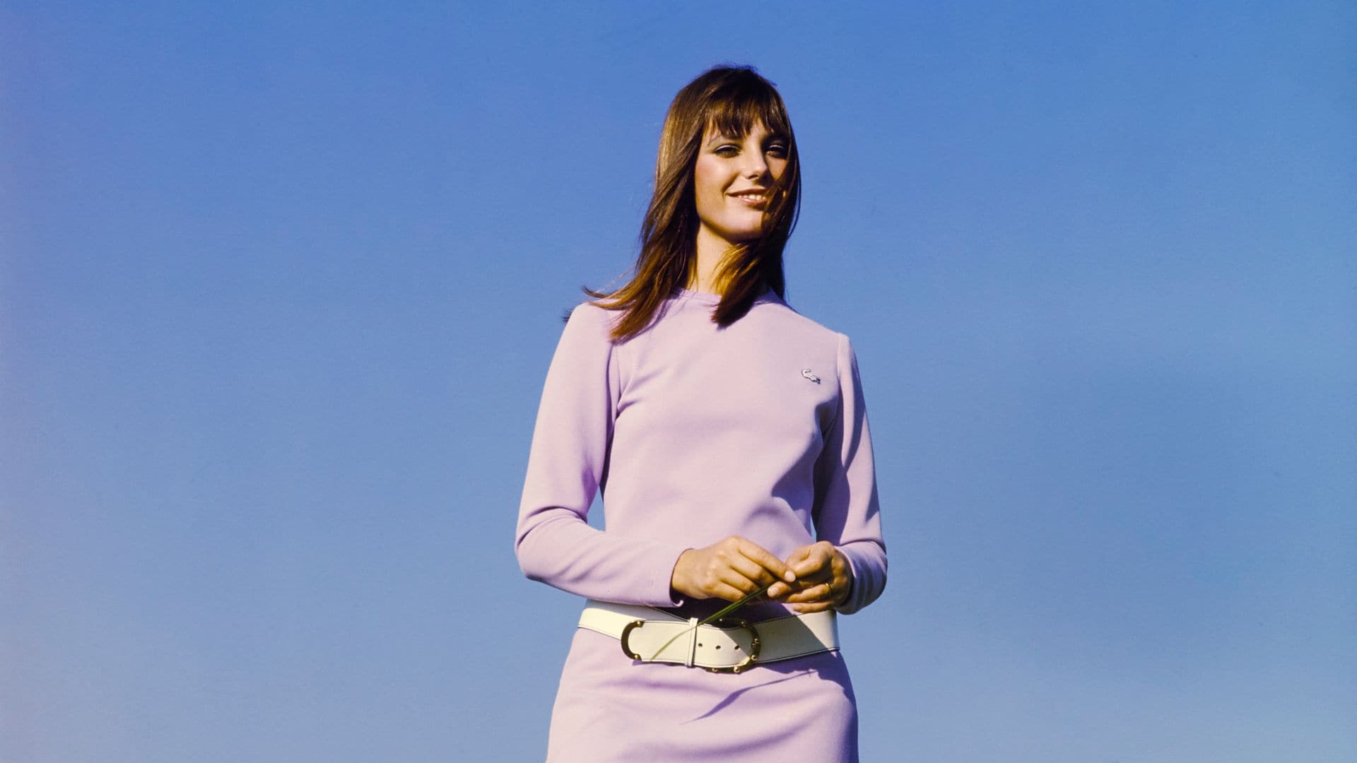 Jane Birkin con vestido corto lila, cinturón y botas blancas