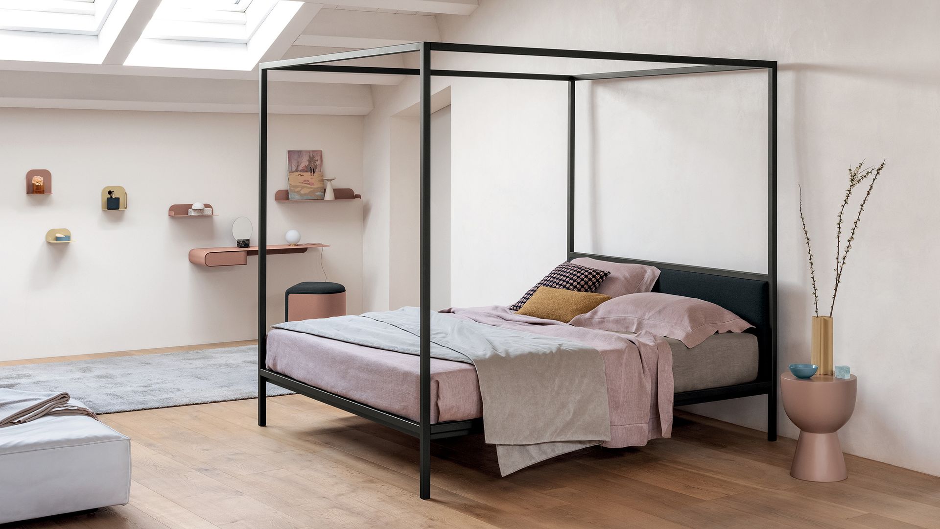 Dormitorio abuhardillado con cama con dosel negro y sábanas rosas