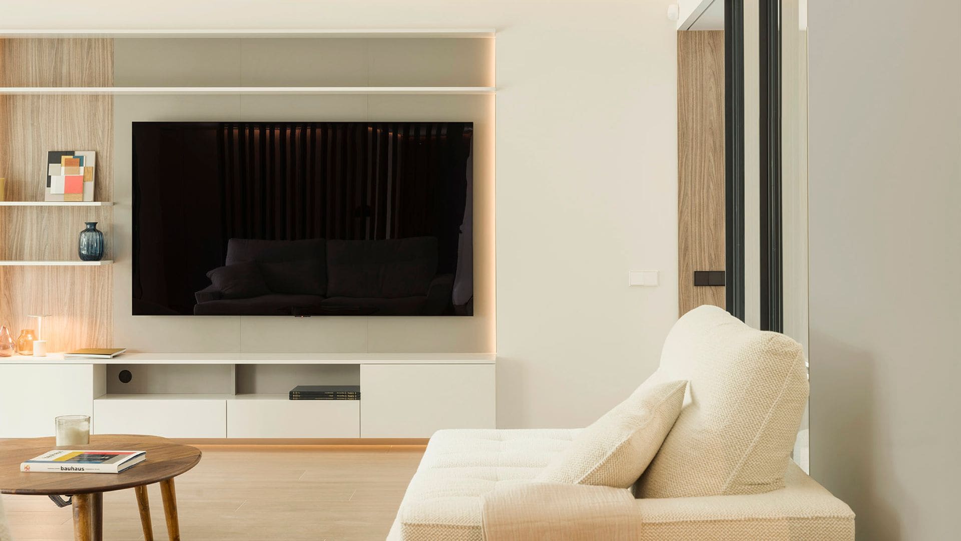 Salón con mueble a medida, televisor colgado en la pared, sofá blanco y mesa de centro de madera