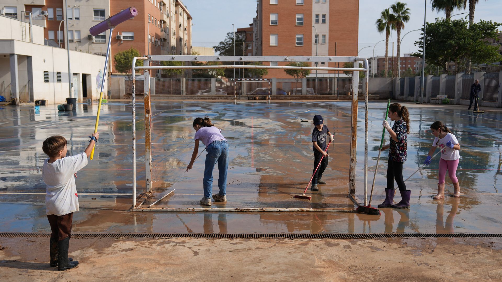 Niños ayudan a limpiar un campo de fútbol afectado por la DANA en Valencia