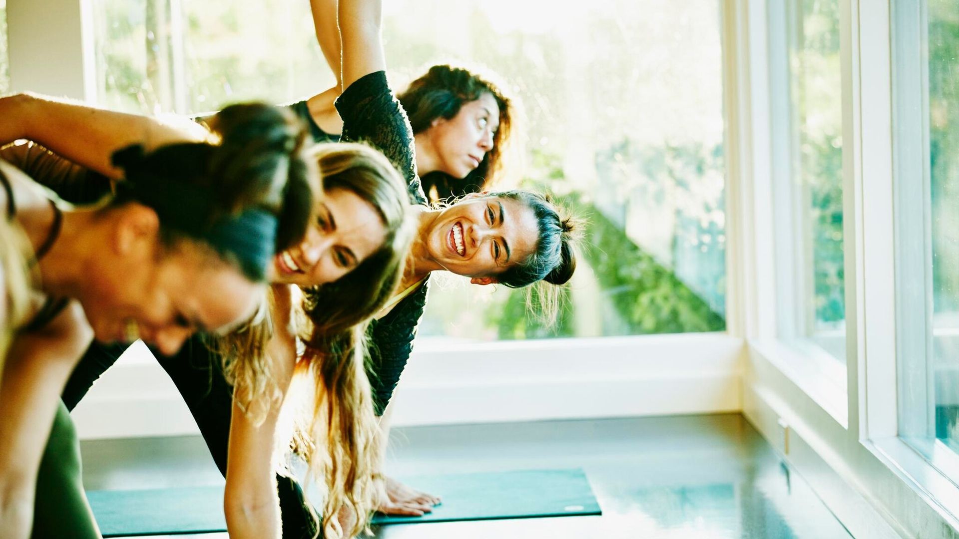 smiling woman laughing with friends during yoga class in studio